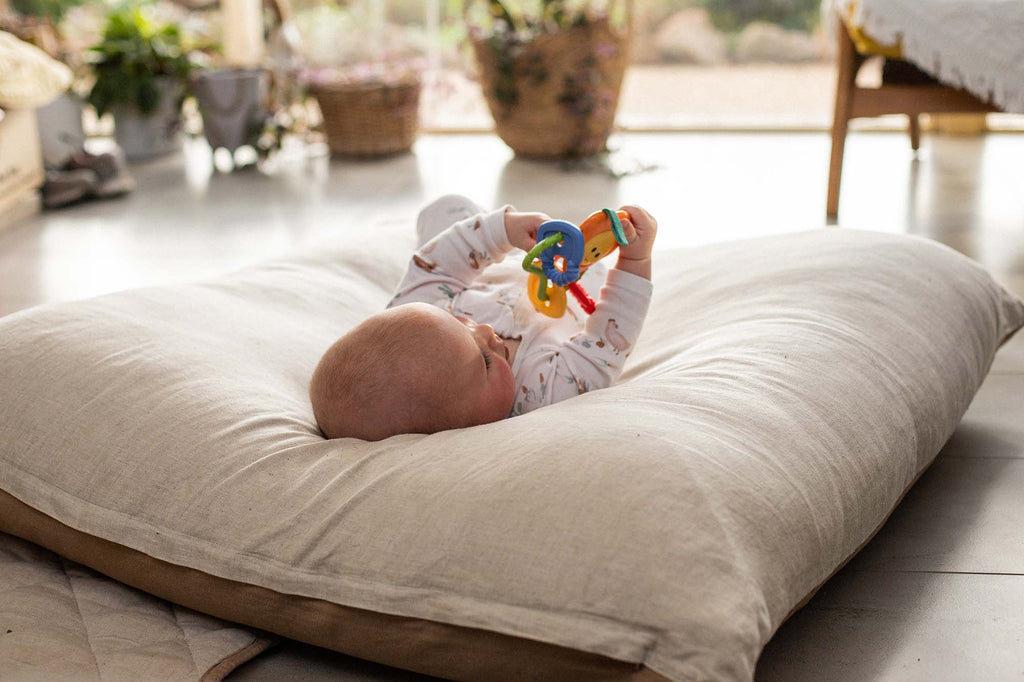 Baby happily playing in a large soft WarrenHill Family floor cushion