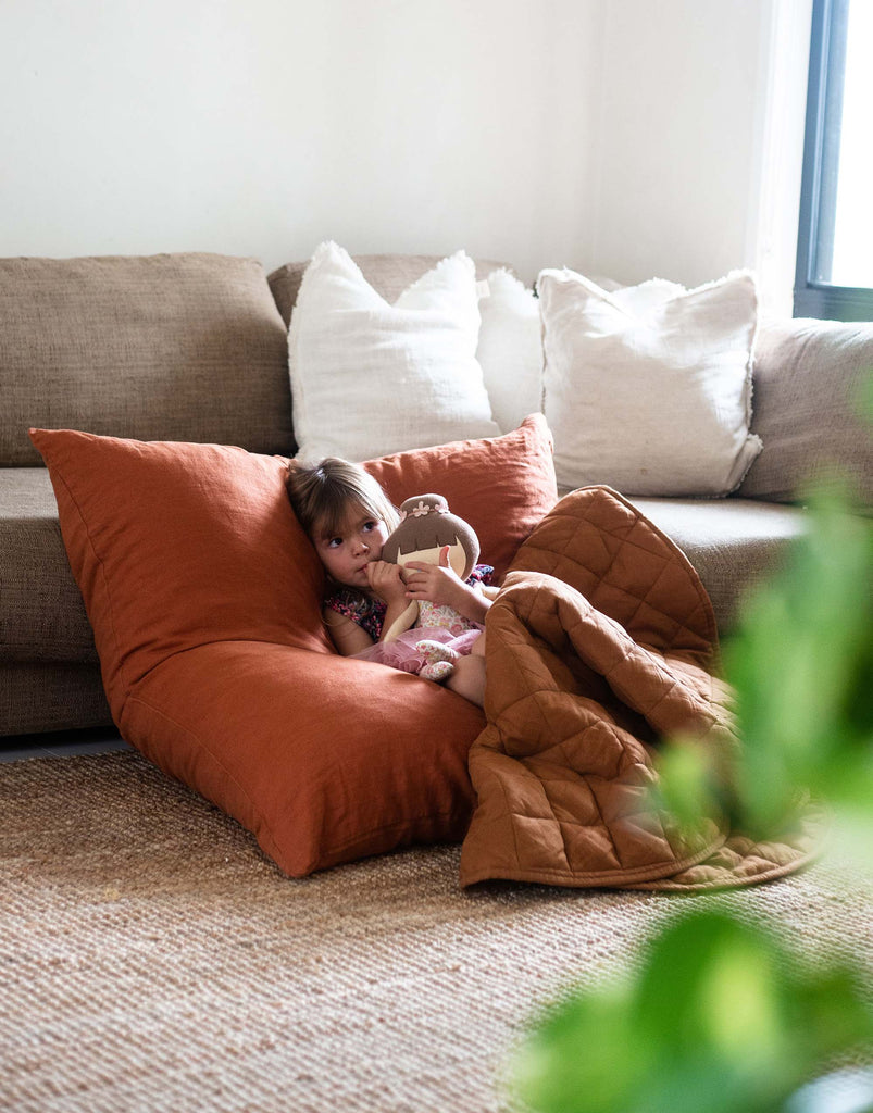 toddler using a family floor cushion as a comfy seat to watch a movie