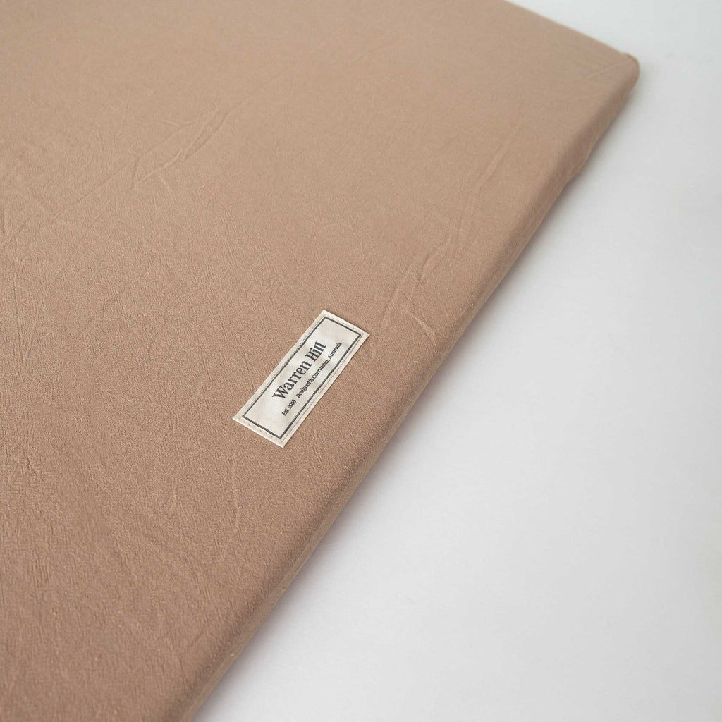 Detailed view of the Warren Hill label stitched onto the Chestnut Padded Play Mat.