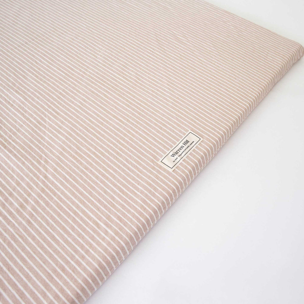 Detailed view of the Warren Hill label stitched onto the Hamptons Stripe Padded Play Mat.