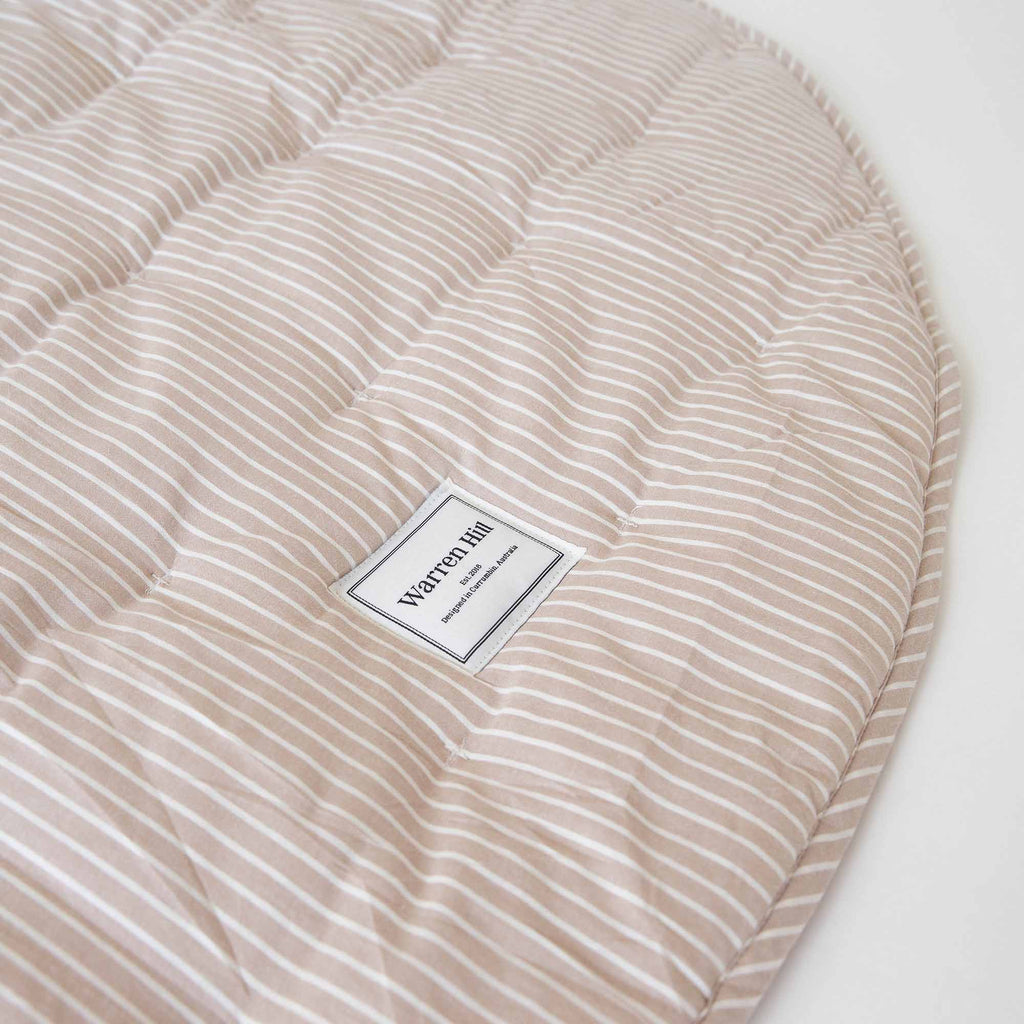 Close-up of the Warren Hill label on the Hamptons Stripe Quilted Cotton Play Mat, showing fine stitching.