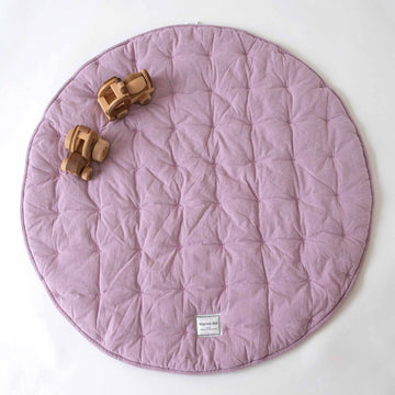 Lilac Cotton Quilted Play Mat by Warren Hill laid flat with wooden toy trucks on top.