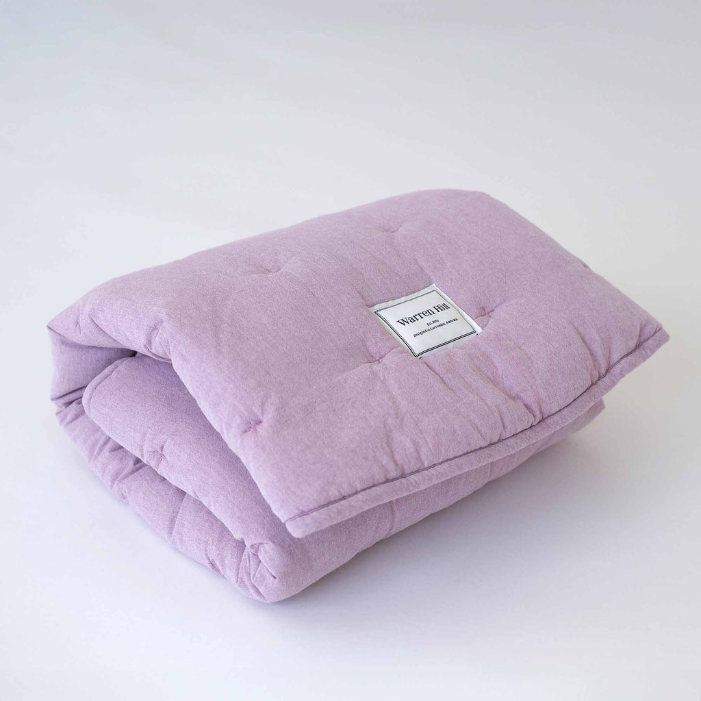 Lilac Cotton Quilted Play Mat neatly folded, showcasing Warren Hill's brand label.