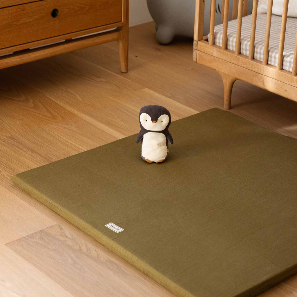 Olive Padded Play Mat next to a cot in a neutral, minimalist nursery