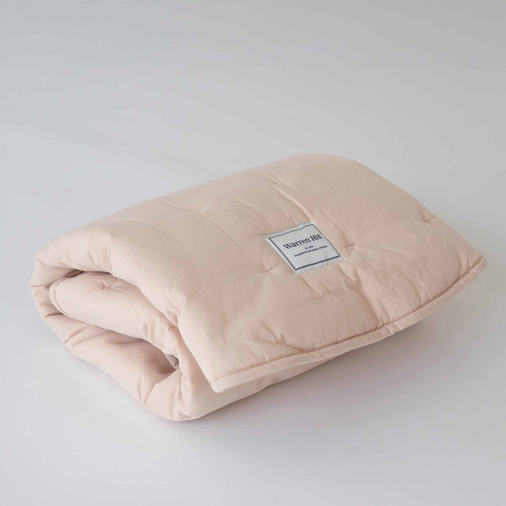 Peach Cotton Quilted Play Mat neatly folded, showcasing Warren Hill's brand label.