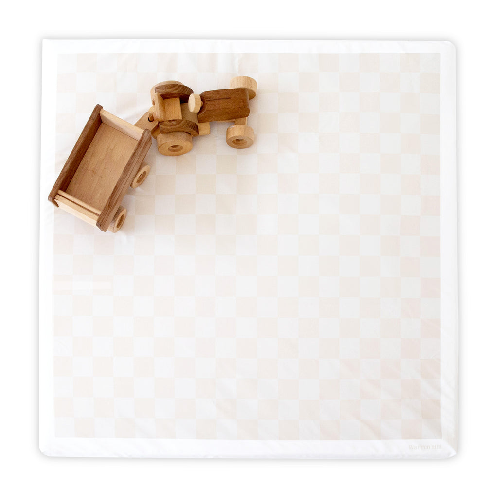 Wipeable Beige Padded Play Mat by Warren Hill with a checkered design and wooden toy trucks on top.