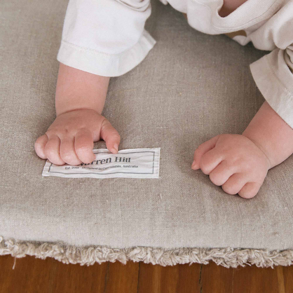 Soft, natural linen fabric with a raw edge finish on the Warren Hill Linen Padded Play Mat.