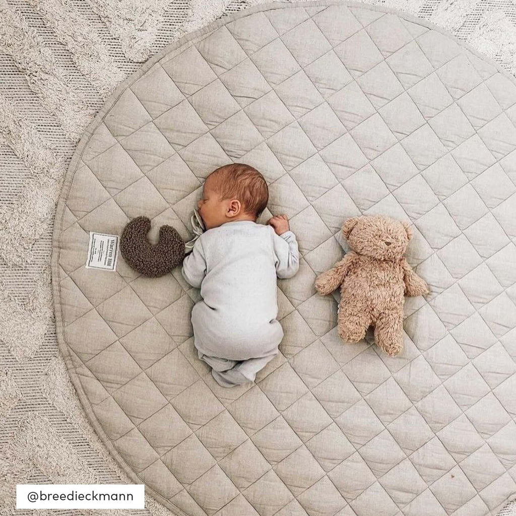 A newborn lying comfortably on the Natural Quilted Linen Play Mat